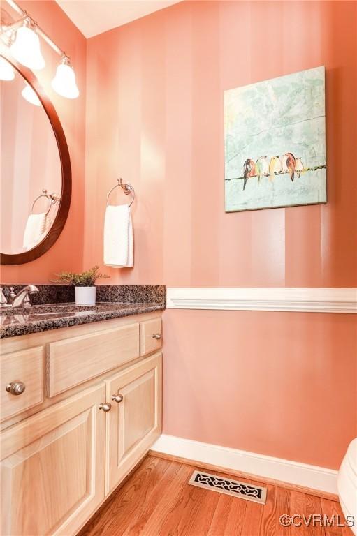 bathroom with vanity, wood finished floors, visible vents, and baseboards