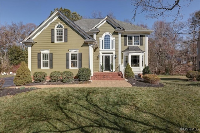 traditional home featuring roof with shingles and a front yard