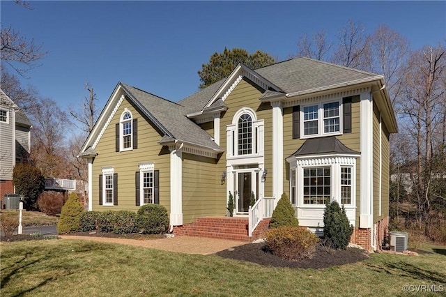 view of front facade with central air condition unit, a front lawn, and roof with shingles