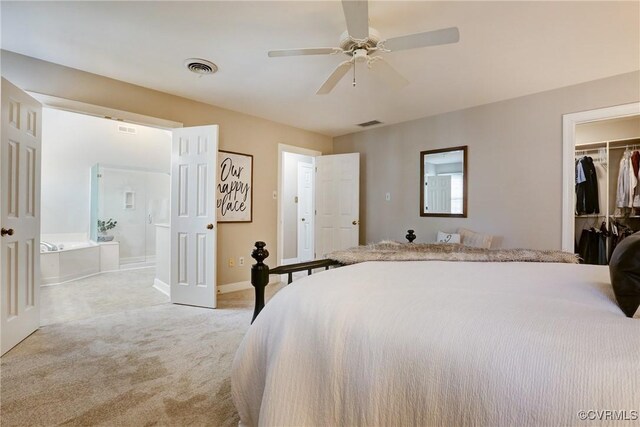 bedroom with light carpet, visible vents, a closet, a walk in closet, and ensuite bath