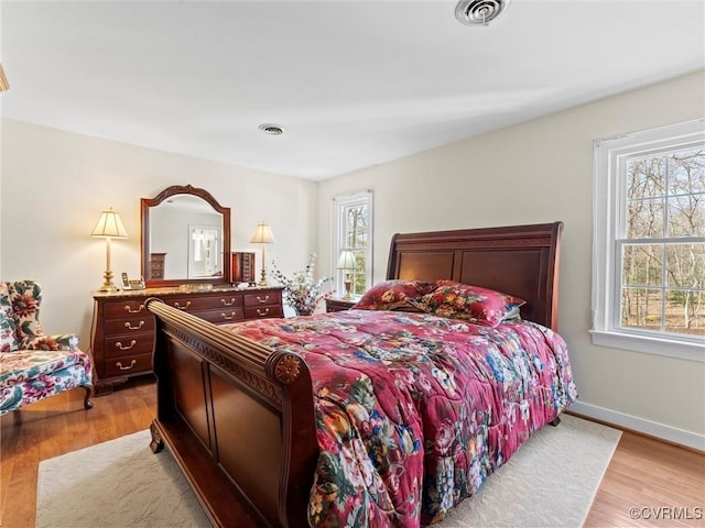 bedroom with visible vents, light wood-style flooring, and baseboards