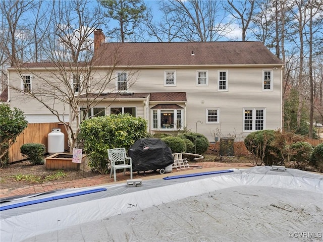 back of property featuring a chimney and fence