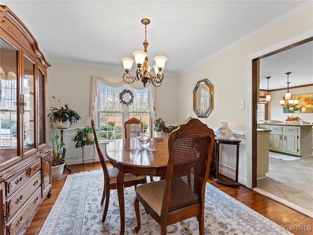 dining area featuring a chandelier, light wood-style flooring, and crown molding