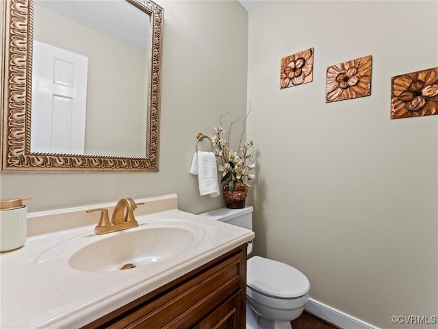 half bath featuring toilet, baseboards, and vanity