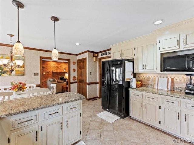 kitchen featuring pendant lighting, cream cabinets, ornamental molding, black appliances, and wallpapered walls