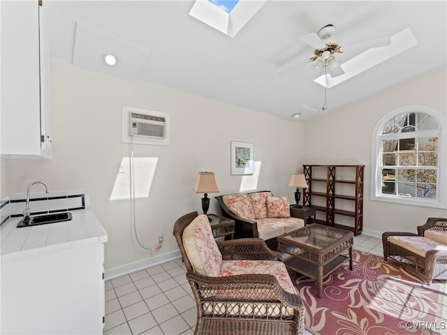 living area featuring lofted ceiling with skylight, a ceiling fan, light tile patterned flooring, and a wall mounted AC