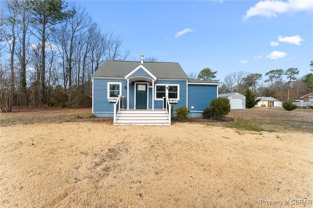 bungalow featuring an outbuilding, a shingled roof, and a front lawn