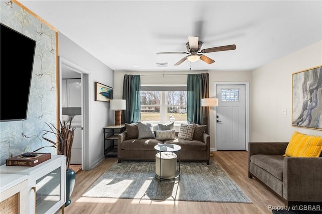 living room with baseboards, ceiling fan, visible vents, and wood finished floors