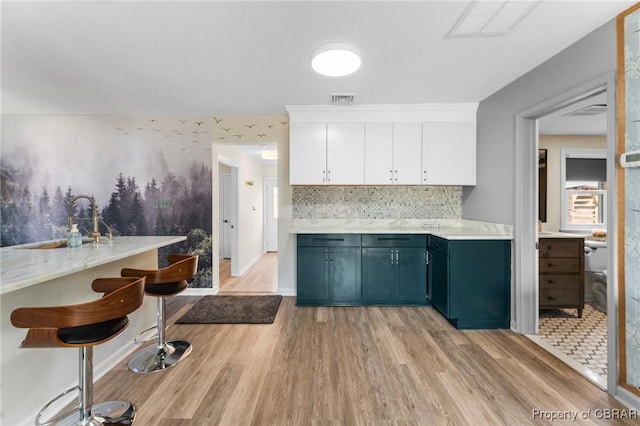 kitchen with light wood finished floors, white cabinetry, visible vents, and light countertops