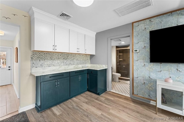 kitchen featuring light countertops, light wood-type flooring, visible vents, and white cabinetry