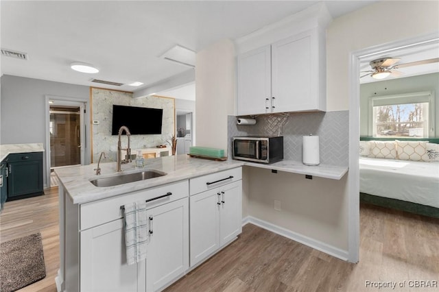 2799 Lake Rd, Lottsburg, VA 22511 - kitchen featuring light wood finished floors, a sink, open floor plan, stainless steel microwave, and tasteful backsplash
