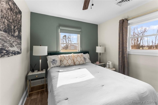 bedroom with wood finished floors, visible vents, baseboards, and multiple windows