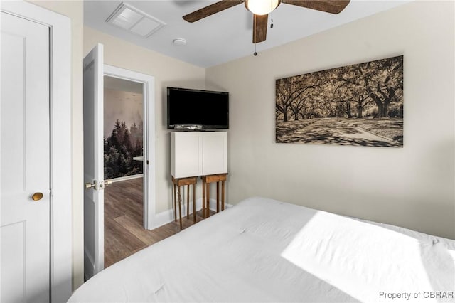 bedroom featuring ceiling fan, wood finished floors, visible vents, and baseboards