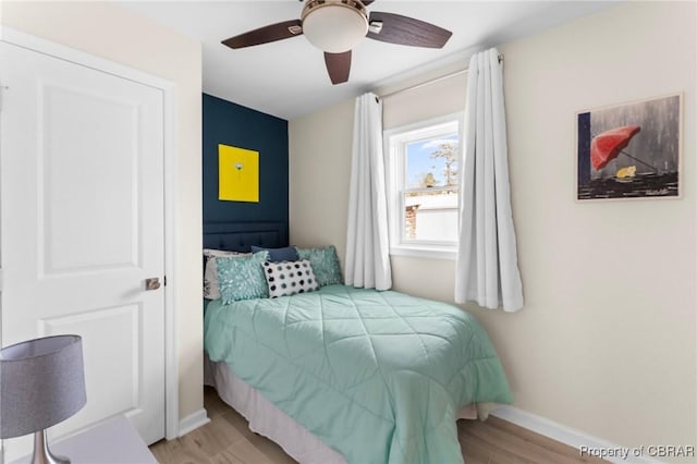 bedroom featuring ceiling fan, light wood-style flooring, and baseboards