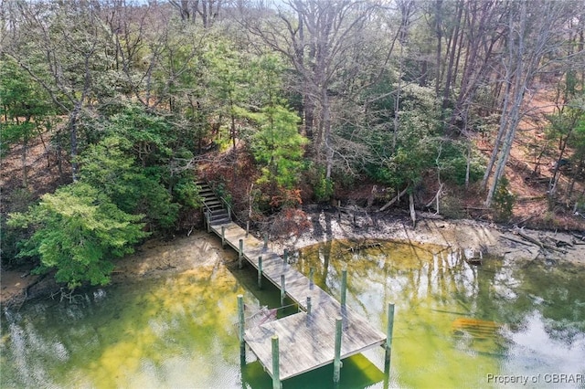 dock area with stairway, a water view, and a view of trees