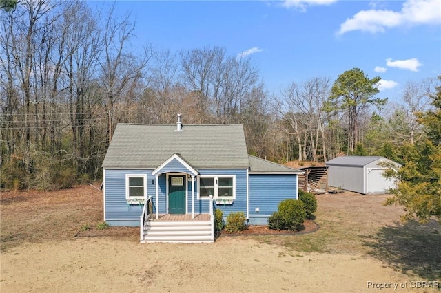 view of front of house with a shingled roof and an outbuilding