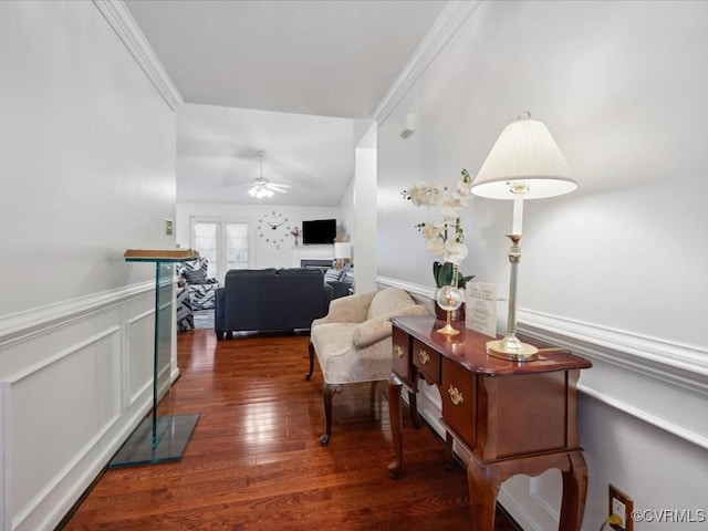 hall featuring ornamental molding, wainscoting, wood-type flooring, and a decorative wall