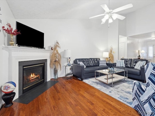 living area with a fireplace with flush hearth, vaulted ceiling, ceiling fan, and wood finished floors