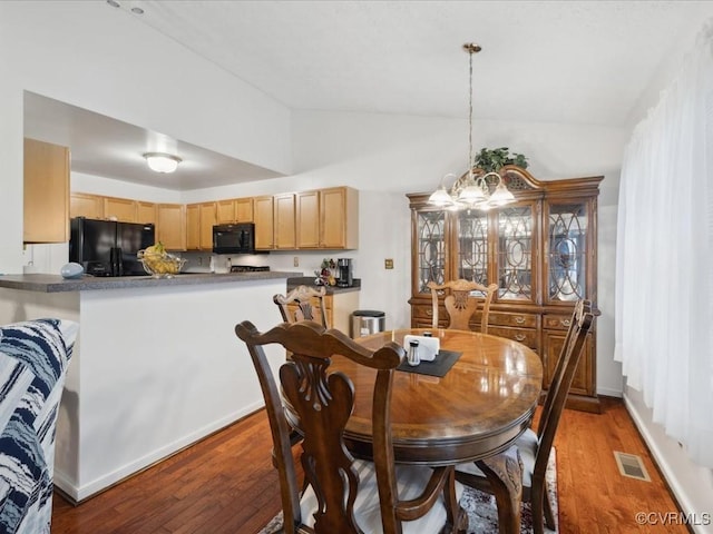 dining area featuring lofted ceiling, light wood-style flooring, visible vents, and an inviting chandelier