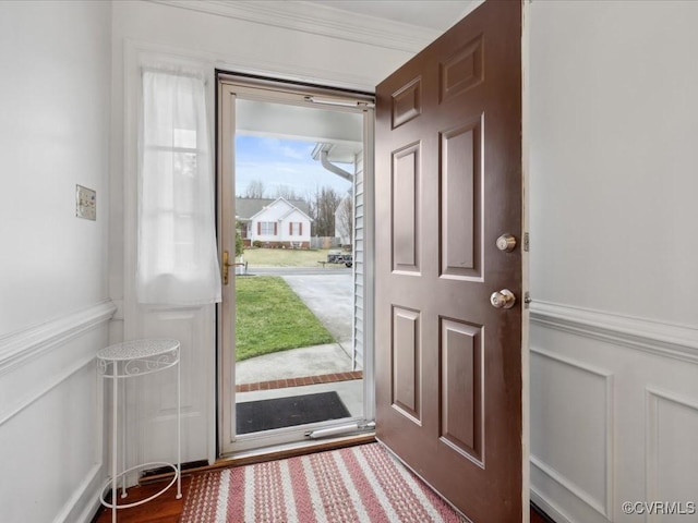 foyer entrance featuring ornamental molding, wainscoting, and a decorative wall