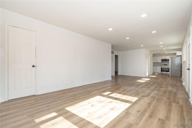 unfurnished living room featuring baseboards, light wood-type flooring, and recessed lighting