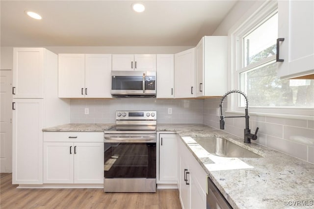 kitchen with stainless steel appliances, a sink, and white cabinetry