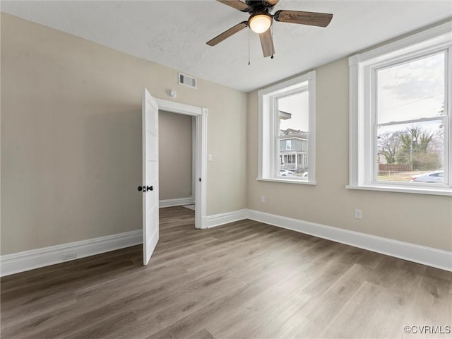 empty room featuring light wood-type flooring, visible vents, and baseboards