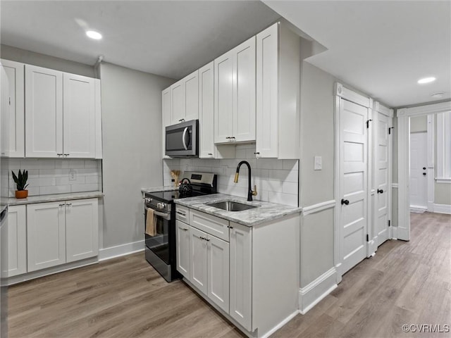 kitchen with white cabinetry, light wood-style flooring, appliances with stainless steel finishes, and a sink