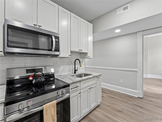 kitchen with light wood finished floors, visible vents, decorative backsplash, stainless steel appliances, and a sink