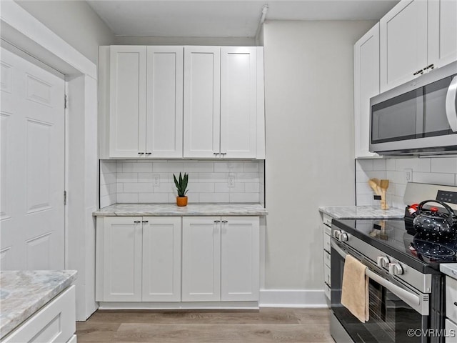 kitchen featuring appliances with stainless steel finishes, light wood-style flooring, and white cabinetry