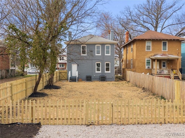 back of property with a fenced front yard, central air condition unit, stucco siding, and entry steps