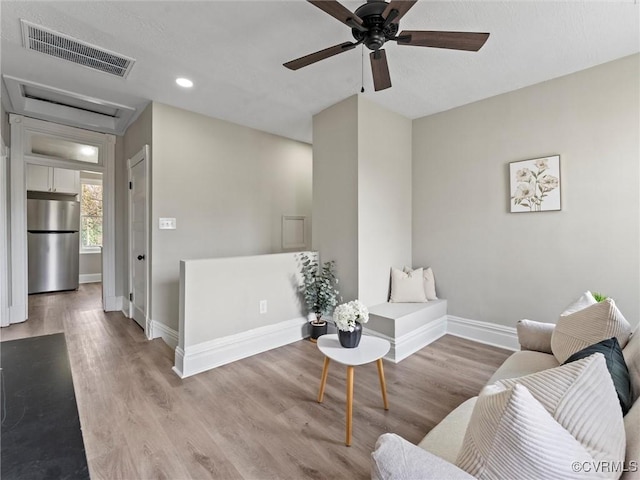 sitting room featuring wood finished floors, visible vents, baseboards, attic access, and ceiling fan