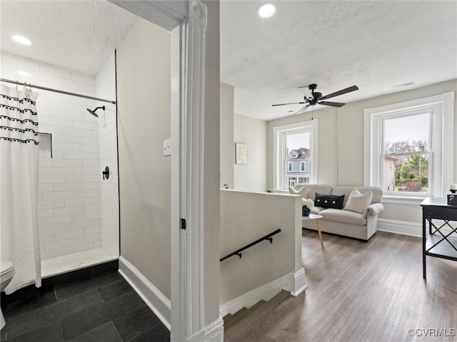 bathroom featuring baseboards, tiled shower, a textured ceiling, and wood finished floors