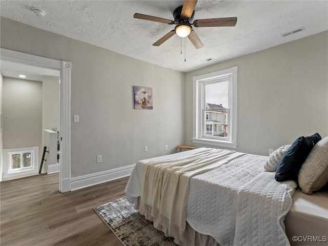 bedroom featuring a textured ceiling, visible vents, dark wood-style flooring, and baseboards