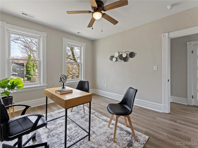 office with visible vents, light wood-style flooring, baseboards, and ceiling fan