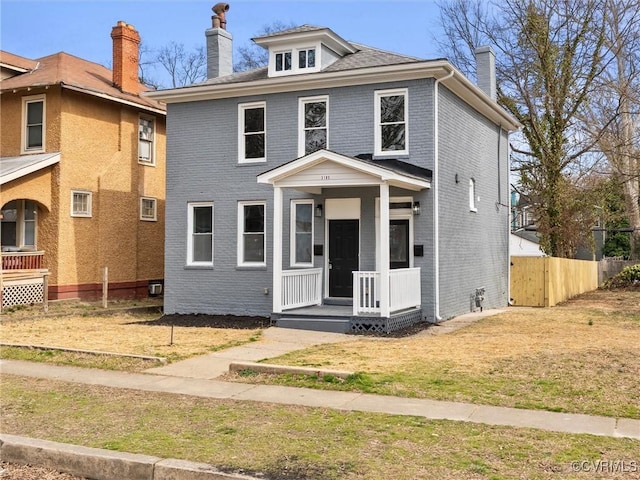 traditional style home with brick siding, a chimney, and fence