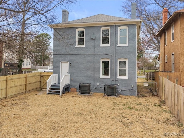 rear view of property featuring cooling unit, a fenced backyard, and a chimney