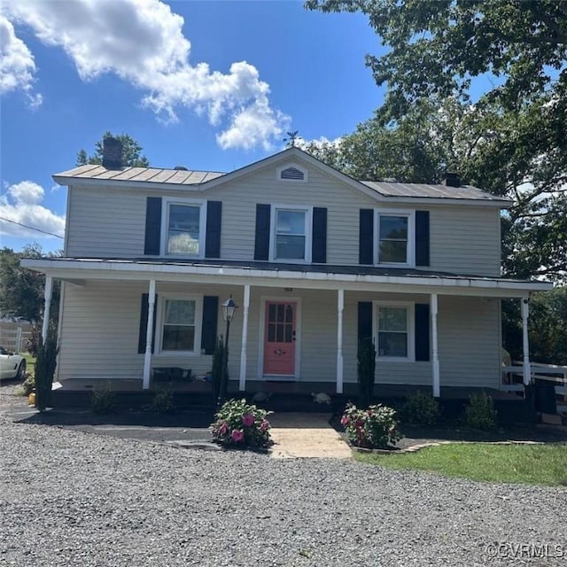 view of front of home with a standing seam roof, metal roof, a porch, and a chimney