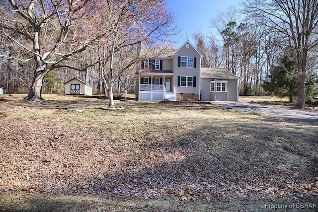 view of front of house with crawl space, covered porch, a storage shed, and an outbuilding