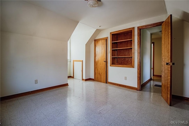 additional living space with built in features, lofted ceiling, baseboards, and tile patterned floors