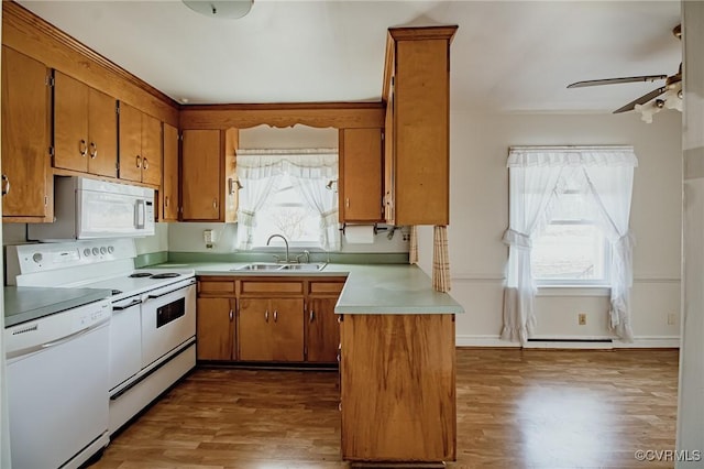 kitchen with light countertops, white appliances, brown cabinetry, and a sink