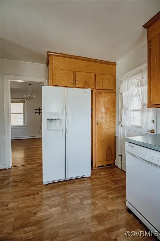 kitchen with white appliances, ornamental molding, brown cabinetry, and wood finished floors