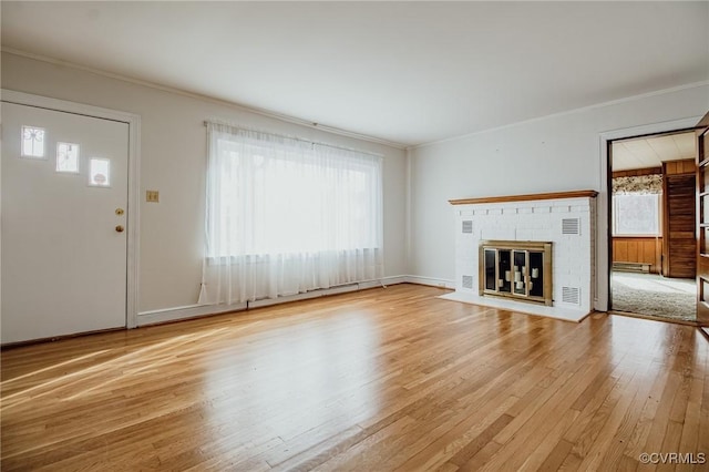 unfurnished living room with baseboards, a brick fireplace, wood finished floors, and crown molding