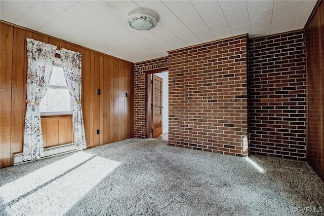 spare room featuring carpet floors, baseboard heating, brick wall, and wooden walls