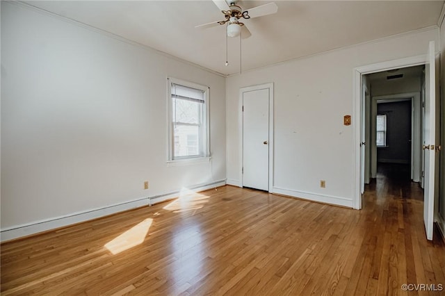 unfurnished bedroom with a baseboard radiator, wood finished floors, a ceiling fan, baseboards, and crown molding