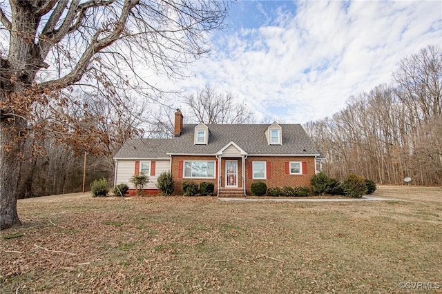 cape cod-style house featuring brick siding, roof with shingles, a chimney, and a front yard