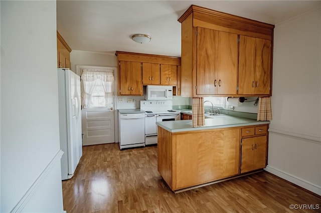 kitchen featuring a peninsula, white appliances, wood finished floors, and brown cabinets