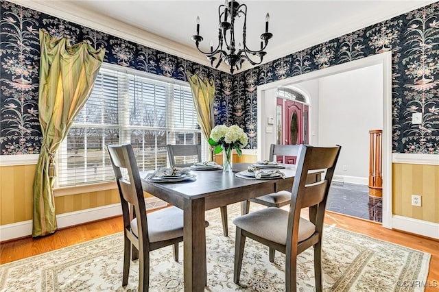 dining space featuring baseboards, wallpapered walls, an inviting chandelier, and wood finished floors