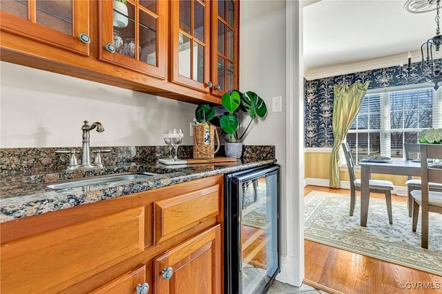 bar with a sink, indoor wet bar, a wainscoted wall, and beverage cooler