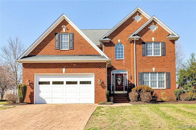 traditional-style home with brick siding, a garage, decorative driveway, and a front lawn